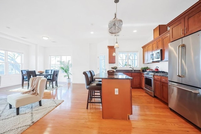 kitchen featuring a breakfast bar area, light wood-style floors, appliances with stainless steel finishes, and a healthy amount of sunlight