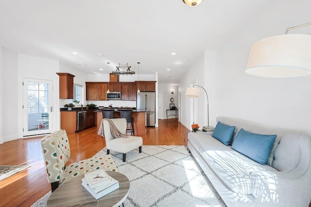 living room with light wood finished floors, recessed lighting, and baseboards