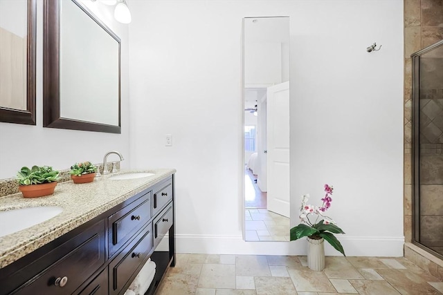 bathroom with a sink, baseboards, tiled shower, and stone tile floors