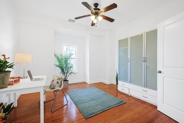 office featuring visible vents, a ceiling fan, baseboards, and wood finished floors