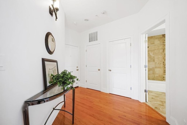 hallway with light wood-style floors and visible vents