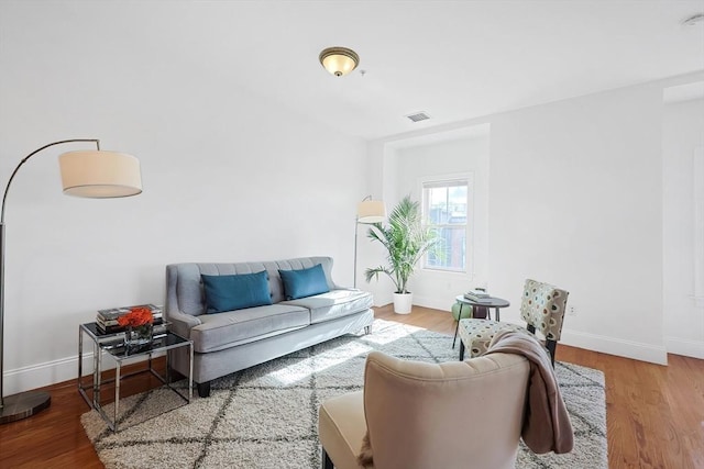 living area with visible vents, baseboards, and wood finished floors