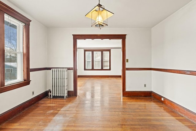 unfurnished room with radiator heating unit, baseboards, and wood finished floors