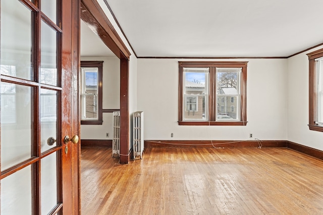 spare room with light wood-style floors, baseboards, and crown molding