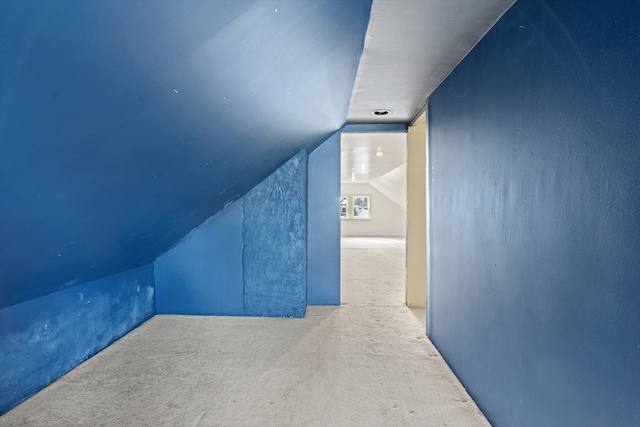 additional living space featuring light colored carpet and vaulted ceiling