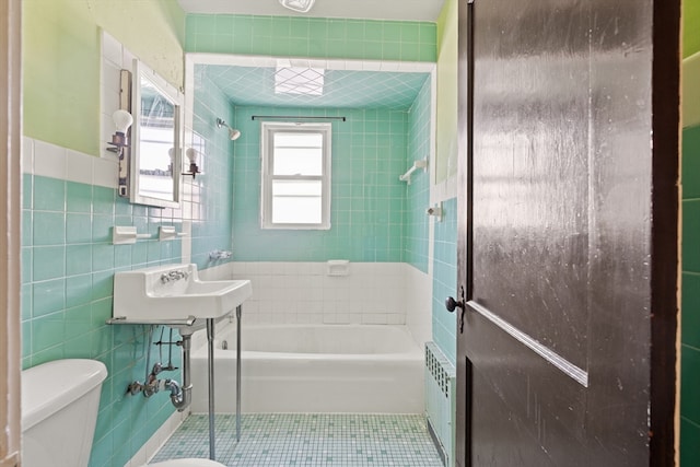 bathroom featuring tile walls, toilet, radiator heating unit, tile patterned flooring, and a sink