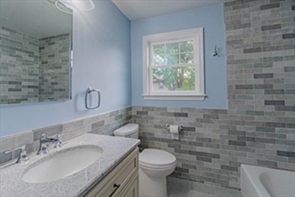 309 Farrington St, Quincy, MA 02170 - bathroom with tile walls, toilet, vanity, and a tub