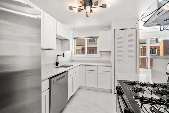 kitchen with a wealth of natural light, white cabinets, appliances with stainless steel finishes, and a sink