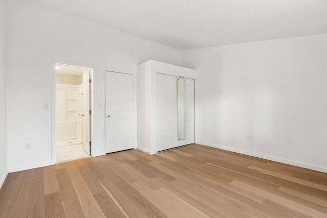 unfurnished bedroom with baseboards, light wood-style flooring, and connected bathroom