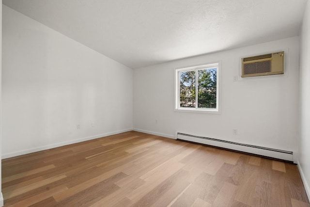 empty room featuring light wood-style floors, baseboards, baseboard heating, and a wall mounted AC