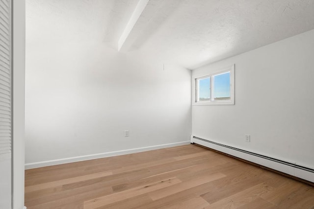 spare room featuring baseboards, light wood-style floors, and baseboard heating