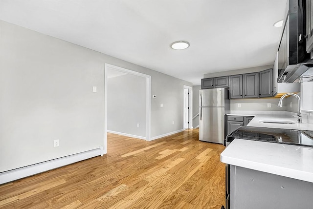 69 Biscuit Hill Dr, Leominster, MA 01453 - kitchen with freestanding refrigerator, baseboard heating, gray cabinets, light countertops, and light wood-type flooring