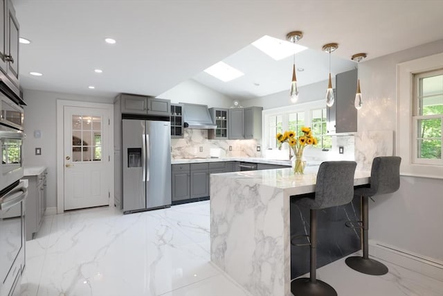 338 Highland St, Weston, MA 02493 - kitchen featuring appliances with stainless steel finishes, gray cabinets, a peninsula, tasteful backsplash, and light stone counters