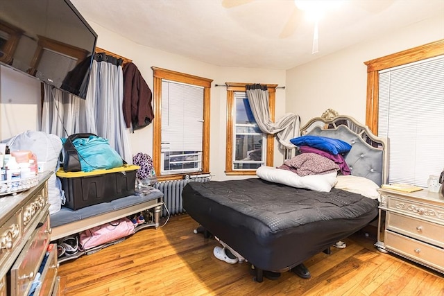 bedroom with hardwood / wood-style flooring, ceiling fan, and radiator heating unit