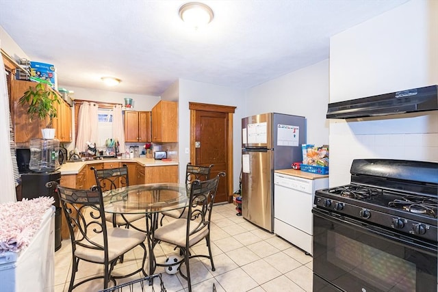 kitchen with light tile patterned flooring, tasteful backsplash, dishwasher, stainless steel fridge, and black range with gas stovetop