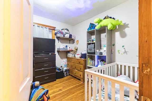 bedroom featuring a crib and light wood-type flooring