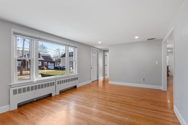 empty room featuring radiator heating unit and light hardwood / wood-style floors