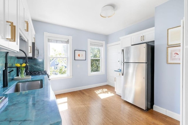 41 Sudan St Unit 3, Boston, MA 02125 - kitchen featuring freestanding refrigerator, light wood finished floors, white cabinets, and backsplash