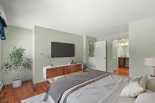 bedroom featuring wood-type flooring, baseboard heating, and ensuite bath