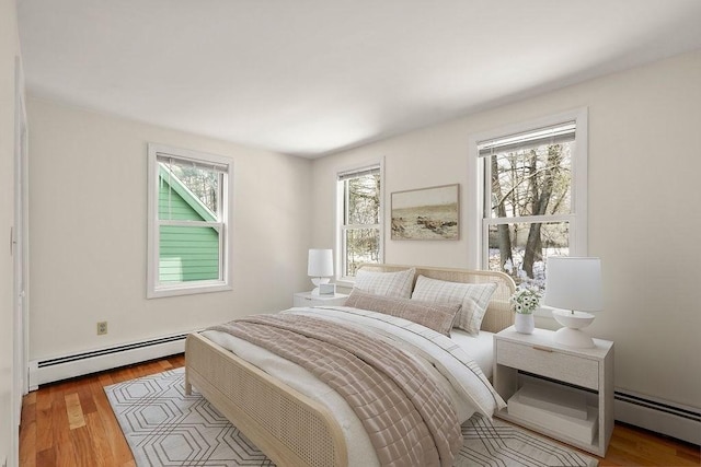 bedroom with baseboard heating and light hardwood / wood-style flooring