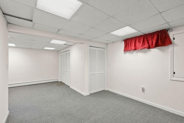 basement with carpet flooring, a drop ceiling, and a baseboard heating unit