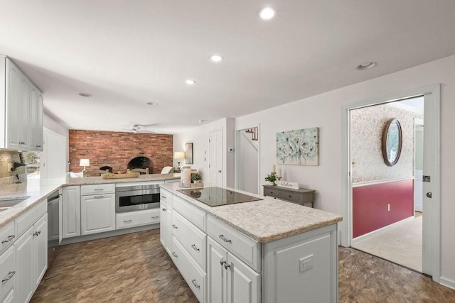 kitchen featuring a kitchen island, white cabinets, ceiling fan, stainless steel appliances, and backsplash