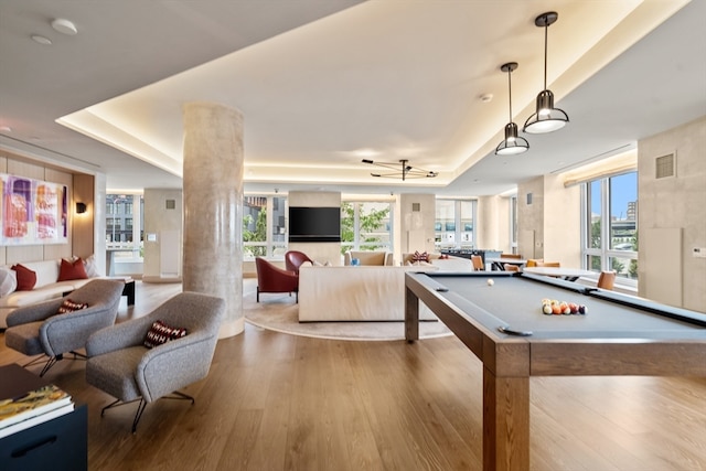 game room with a healthy amount of sunlight, a raised ceiling, visible vents, and wood finished floors