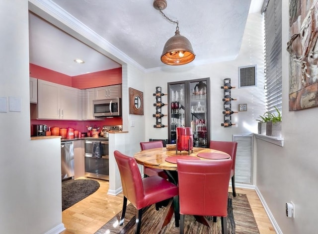 dining room featuring crown molding and light hardwood / wood-style floors