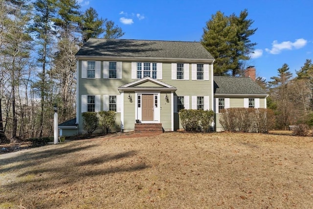 colonial-style house with roof with shingles and a chimney