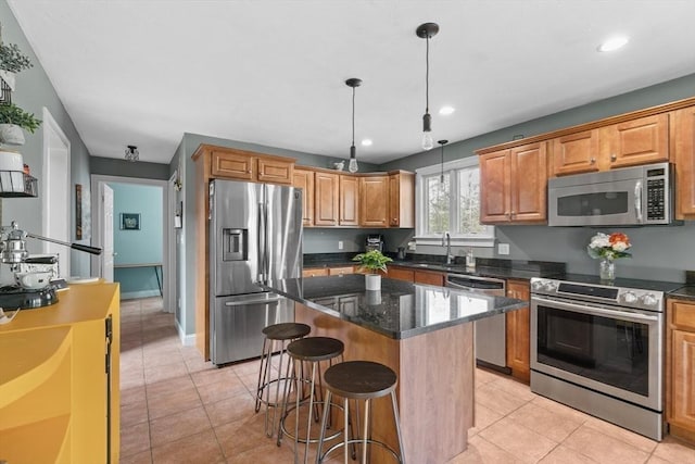 kitchen with decorative light fixtures, a kitchen breakfast bar, a center island, stainless steel appliances, and light tile patterned floors