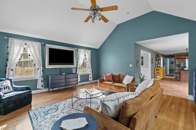 living area with a ceiling fan, lofted ceiling, wood finished floors, and baseboards