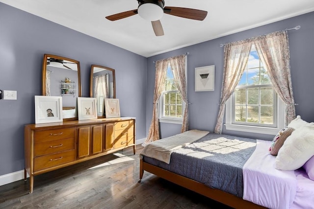 bedroom featuring dark wood finished floors, multiple windows, baseboards, and ceiling fan