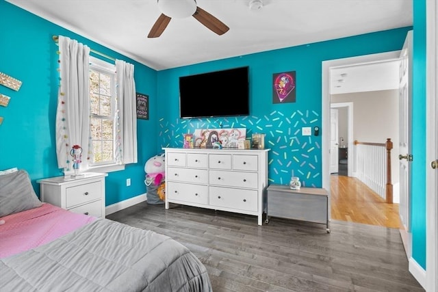 bedroom with an accent wall, wood finished floors, baseboards, and wallpapered walls