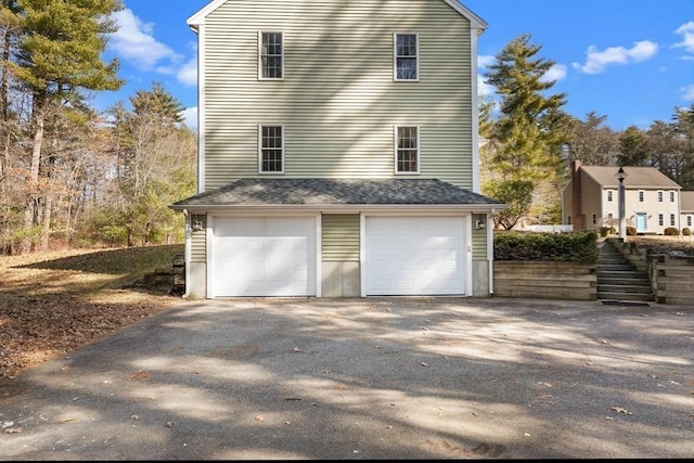 view of side of home with aphalt driveway and an attached garage