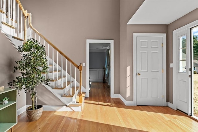 foyer entrance featuring baseboards, wood finished floors, and stairs