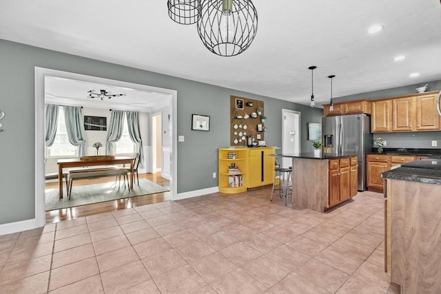 kitchen with light tile patterned floors, stainless steel fridge, a center island, and a breakfast bar area