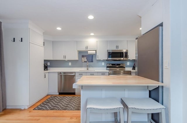 300 Falmouth Rd Unit 12A, Mashpee, MA 02649 - kitchen with stainless steel appliances, a breakfast bar area, light countertops, light wood-style floors, and white cabinetry