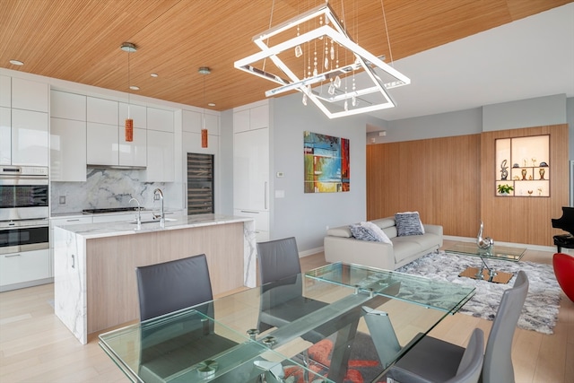 dining room featuring sink, light wood-type flooring, a chandelier, and wooden ceiling