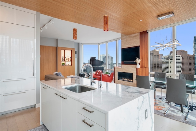 kitchen with an island with sink, white cabinetry, light hardwood / wood-style flooring, and sink