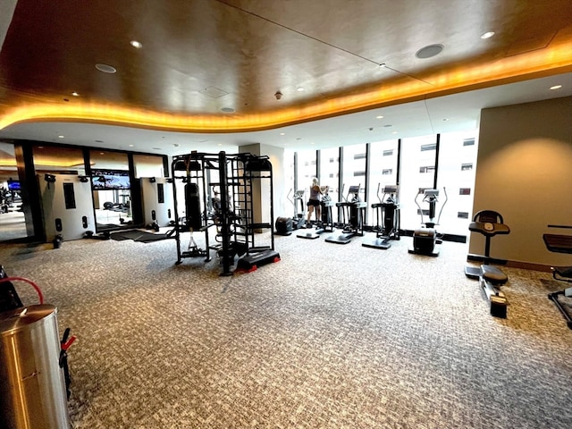 gym featuring floor to ceiling windows, carpet, and a tray ceiling