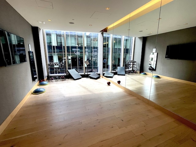 workout area featuring a wall of windows and hardwood / wood-style floors