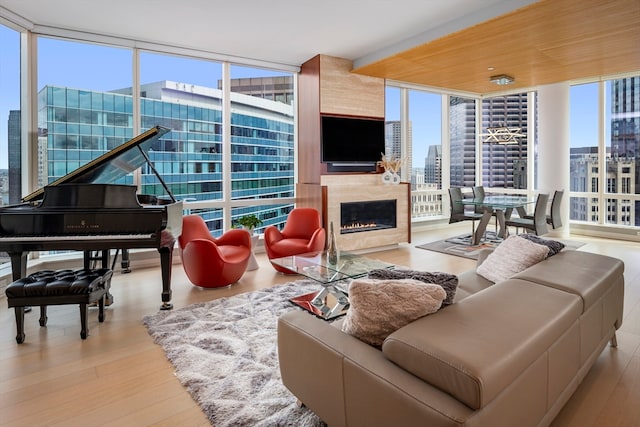 living room with light hardwood / wood-style floors, floor to ceiling windows, a premium fireplace, and plenty of natural light