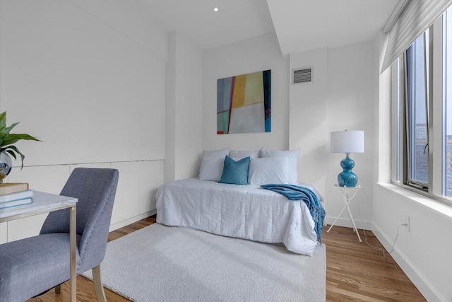 bedroom with baseboards, visible vents, and wood finished floors