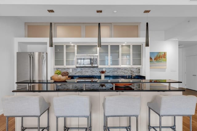 kitchen with stainless steel appliances, tasteful backsplash, dark countertops, and white cabinetry