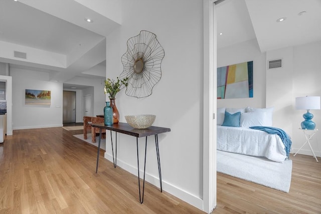 hall featuring baseboards, visible vents, and wood finished floors