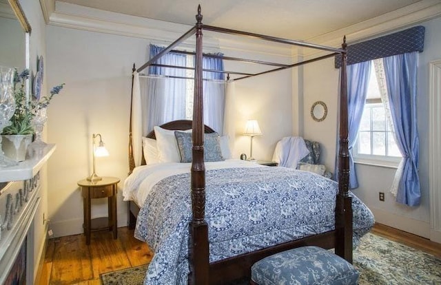 bedroom with baseboards, ornamental molding, wood finished floors, and an inviting chandelier