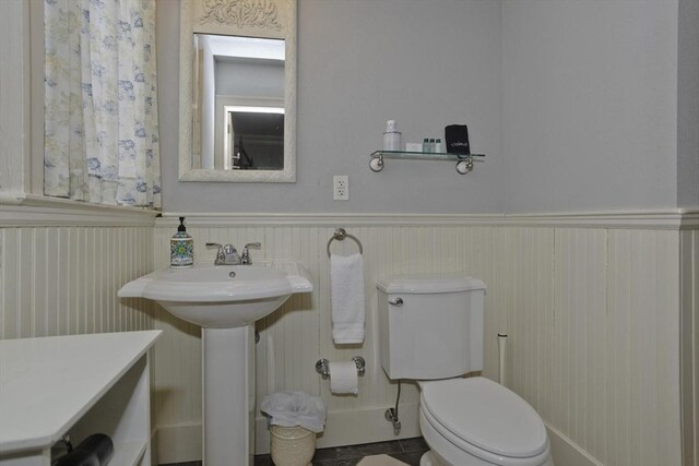 half bath featuring a sink, toilet, and wainscoting