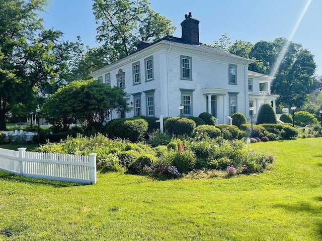 exterior space featuring fence, a chimney, and a lawn