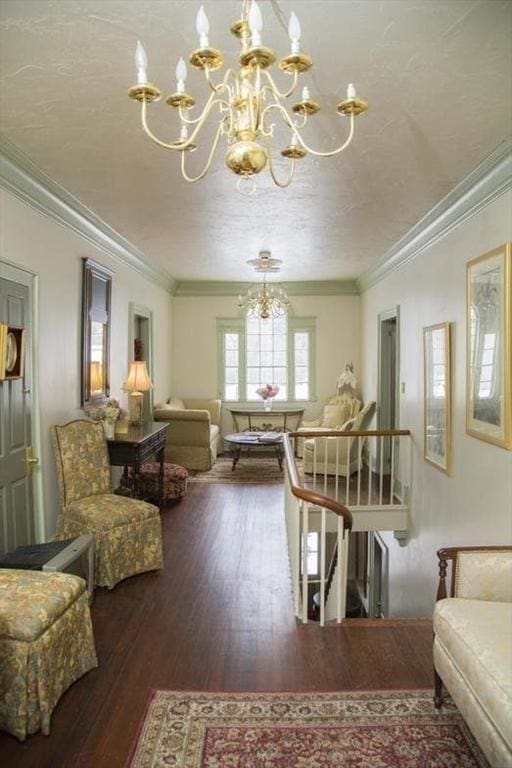 sitting room featuring an upstairs landing, wood finished floors, crown molding, a textured ceiling, and a chandelier