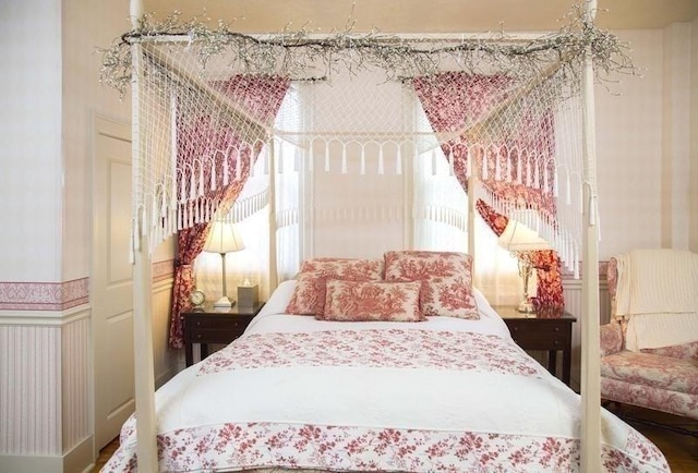 bedroom featuring wainscoting and a decorative wall